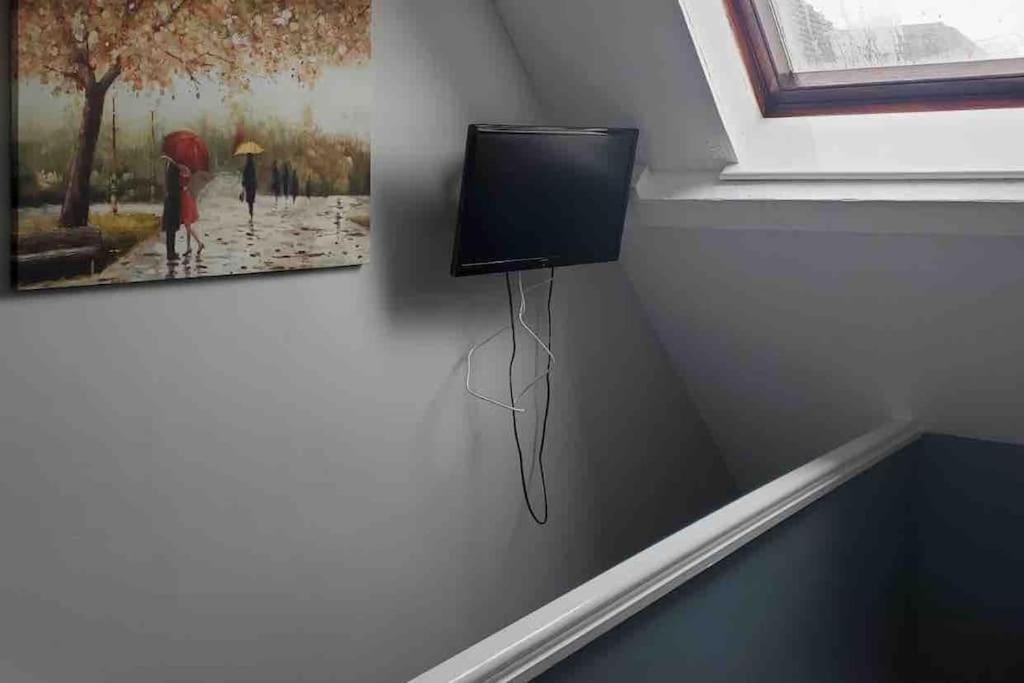a tv on a wall with a picture of two people with umbrellas at Tiny one bedroom house in Mablethorpe