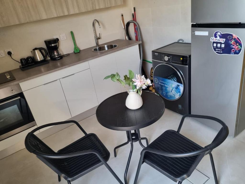 een keuken met een tafel en 2 stoelen en een koelkast bij شقق السيف الفندقية in Riyad