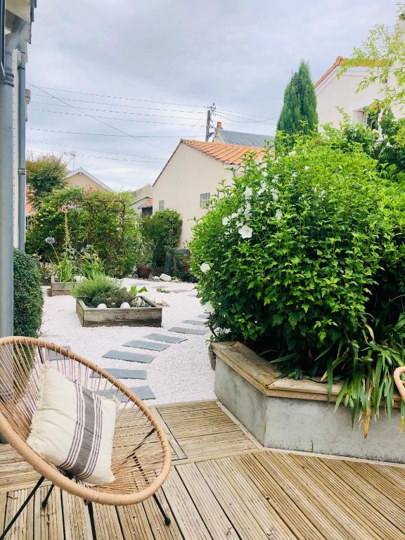 a patio with a rattan chair and some bushes at Villa Einigriv in Châtelaillon-Plage