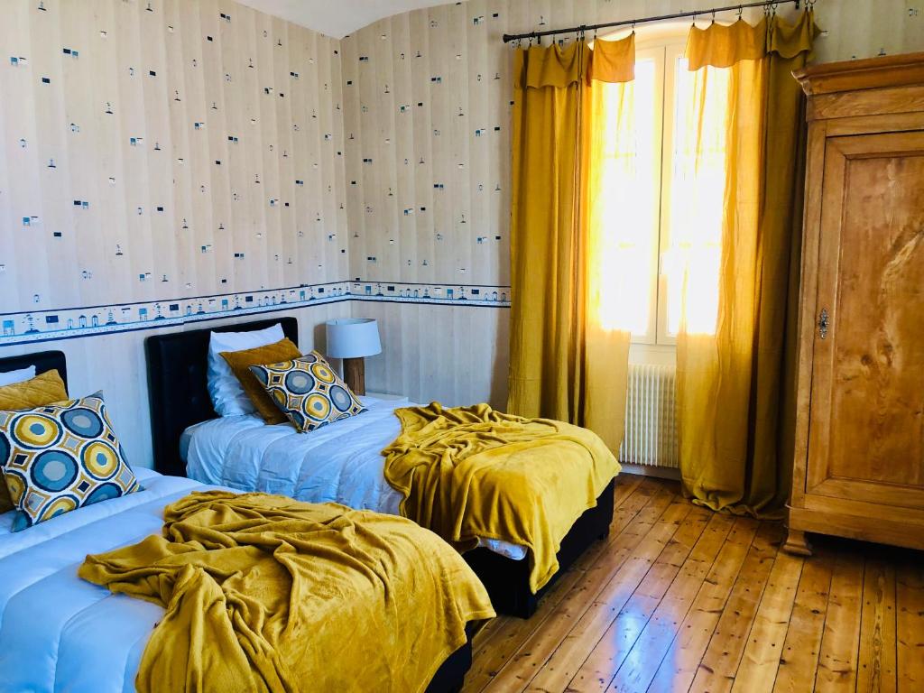 a bedroom with two beds with yellow sheets and a window at Villa Einigriv in Châtelaillon-Plage