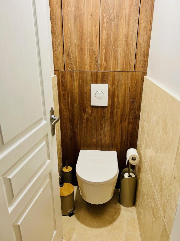 a bathroom with a toilet with a wooden wall at Villa Einigriv in Châtelaillon-Plage