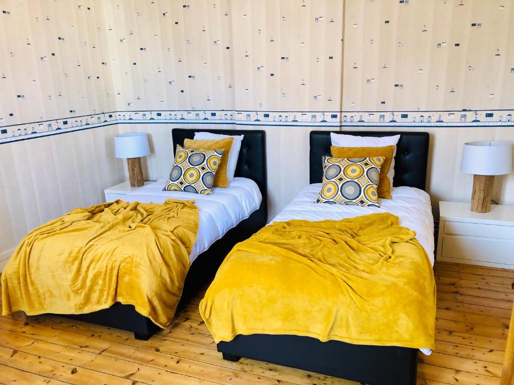 two beds with yellow blankets and pillows in a room at Villa Einigriv in Châtelaillon-Plage