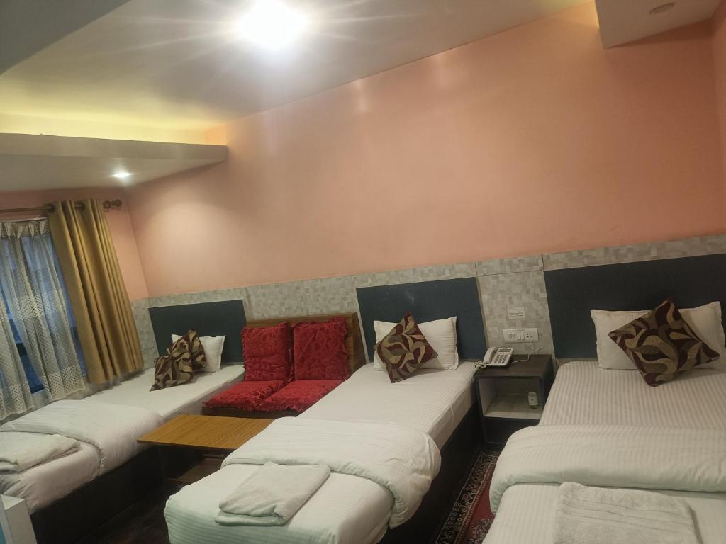 een kamer met drie bedden met kussens erop bij Express Myagdi Hotel Pvt Ltd in Kathmandu