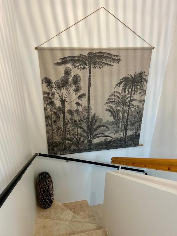 a mural of palm trees on a wall in a stair case at Villa Einigriv in Châtelaillon-Plage