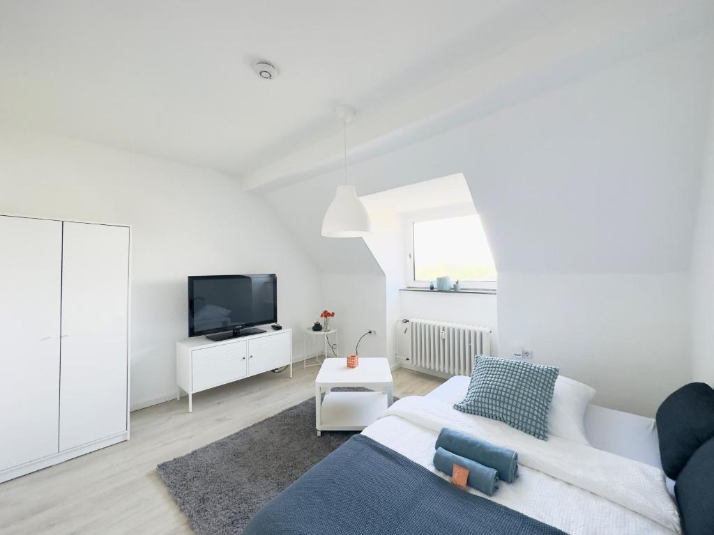 ein weißes Wohnzimmer mit einem weißen Sofa und einem TV in der Unterkunft Möbliertes Apartment in Bochum-nahe Jahrhunderthalle in Bochum