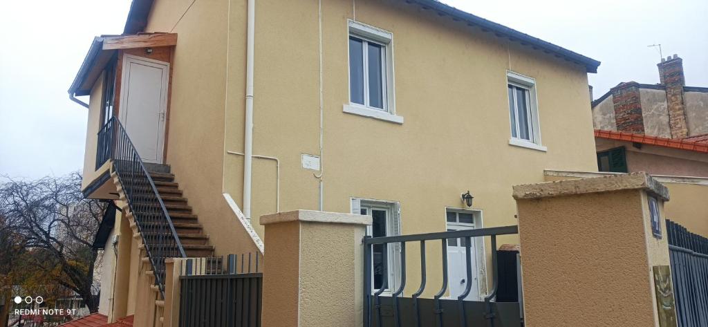 une maison jaune avec un escalier et une clôture dans l'établissement Chez ANNE-SOPHIE, à Villeurbanne