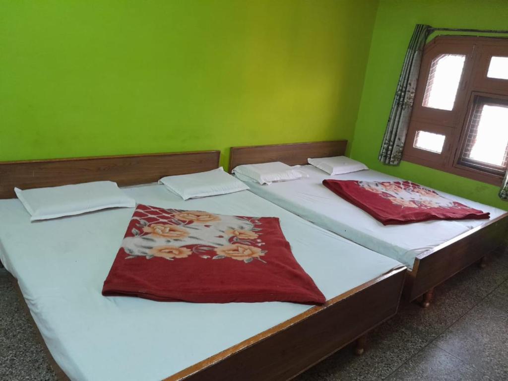 two twin beds in a room with green walls at Hotel Gayatri Guest House Haridwar Near Railway Station - Ganga Ghat - Best Hotel in Haridwar in Haridwār