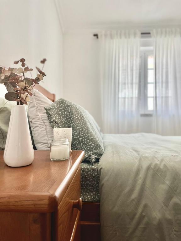 a bedroom with a bed and a vase of flowers on a table at Sabugal Comfort - Central Castelo in Sabugal