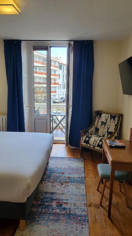 Schlafzimmer mit einem Bett, einem Schreibtisch und einem Fenster in der Unterkunft Grand Hôtel de la Poste in Saint-Jean-de-Luz