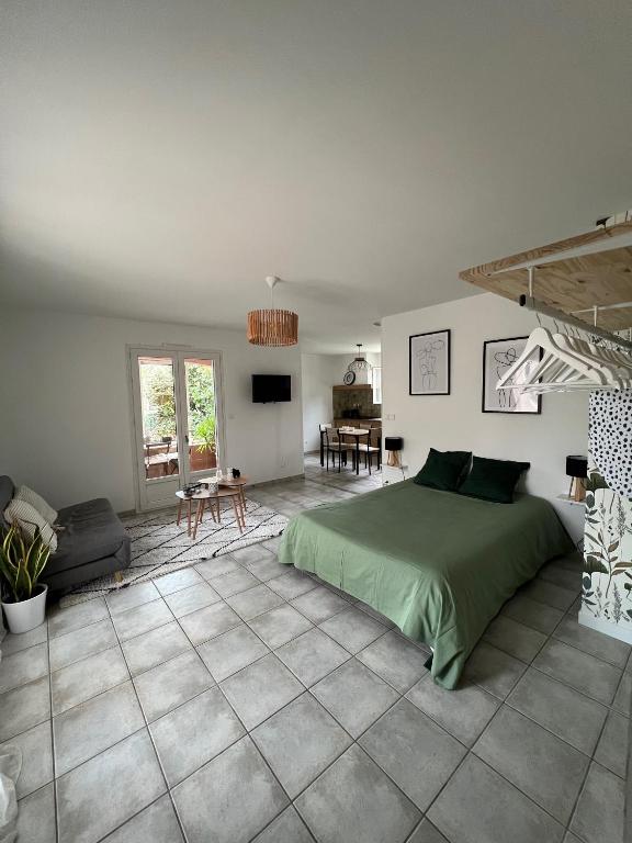 Cet appartement comprend une chambre avec un lit vert et un salon. dans l'établissement Grand studio avec véranda et parking, à Auch