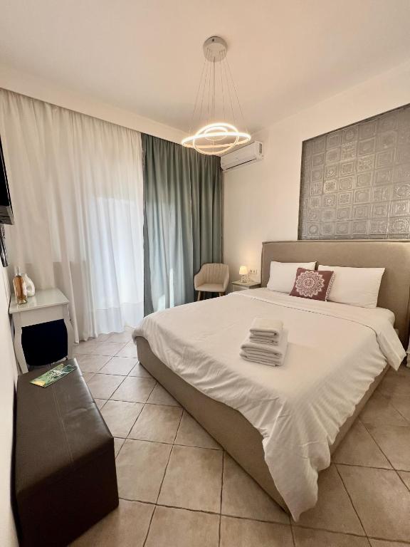 um quarto com uma grande cama branca e uma cadeira em City lux apartment 2 em Serres