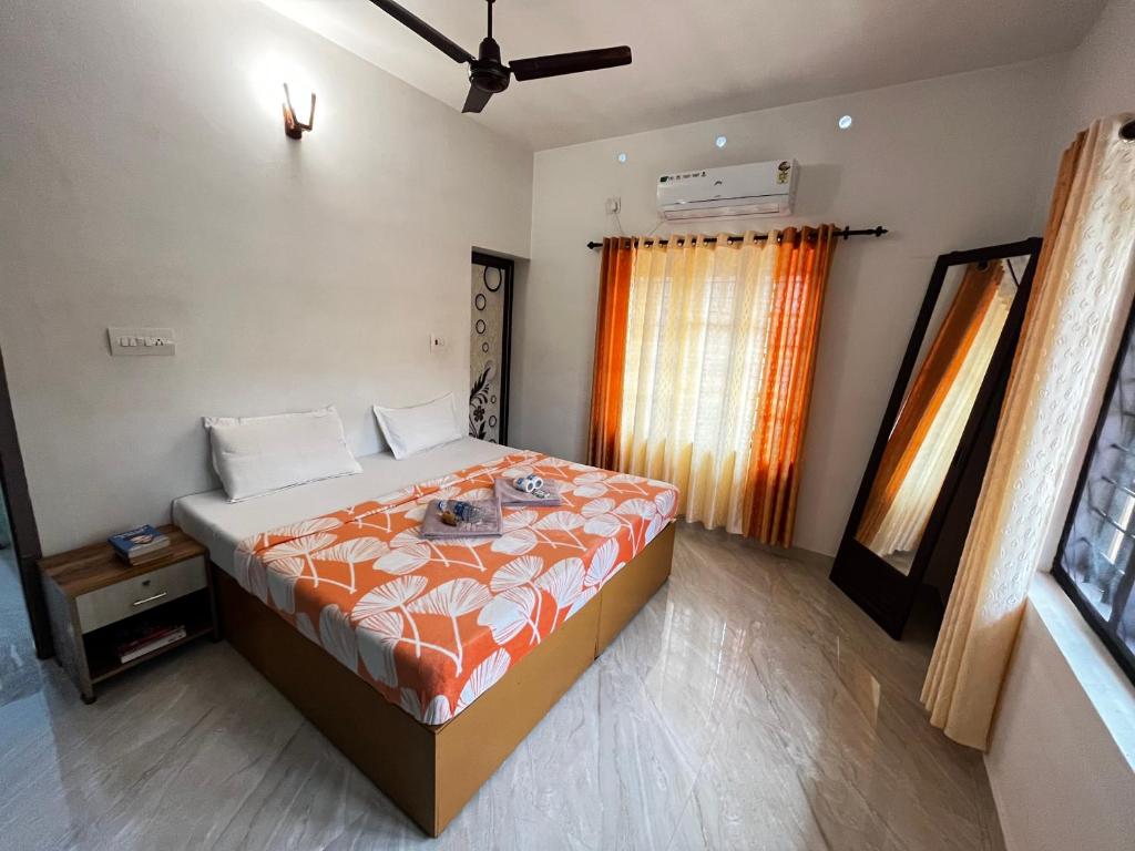 a bedroom with a bed with an orange comforter at Paddy N Canal Homestay in Alleppey