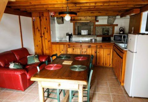 uma cozinha com uma mesa de madeira e um sofá vermelho em La ch'tiote meizou em Mazet-Saint-Voy