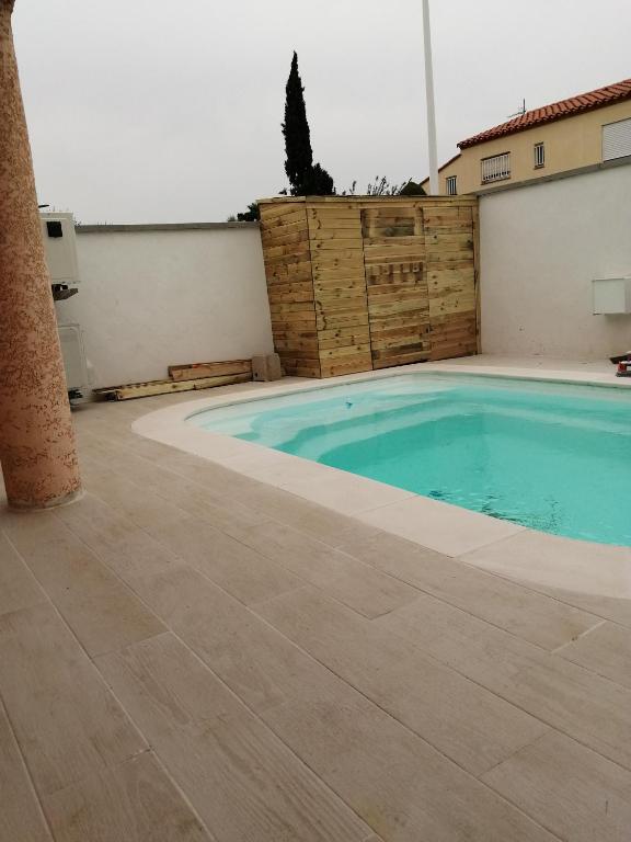 une piscine avec du carrelage et un bâtiment dans l'établissement Maison cosy avec piscine, à Saleilles