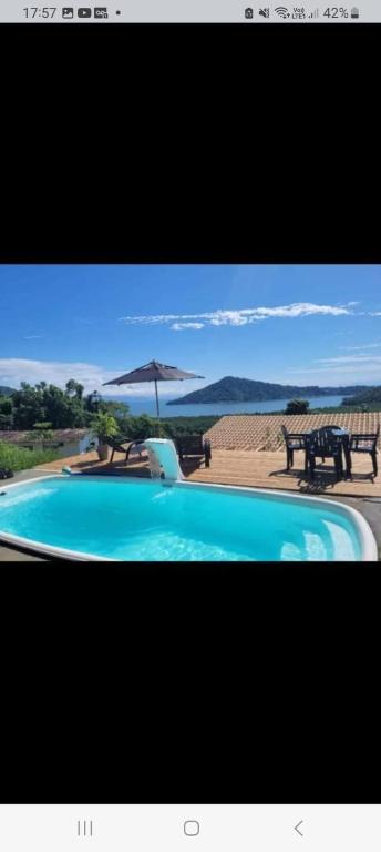 einen Pool mit Sonnenschirm, Tisch und Stühlen in der Unterkunft Suítes mirante corumbê in Paraty
