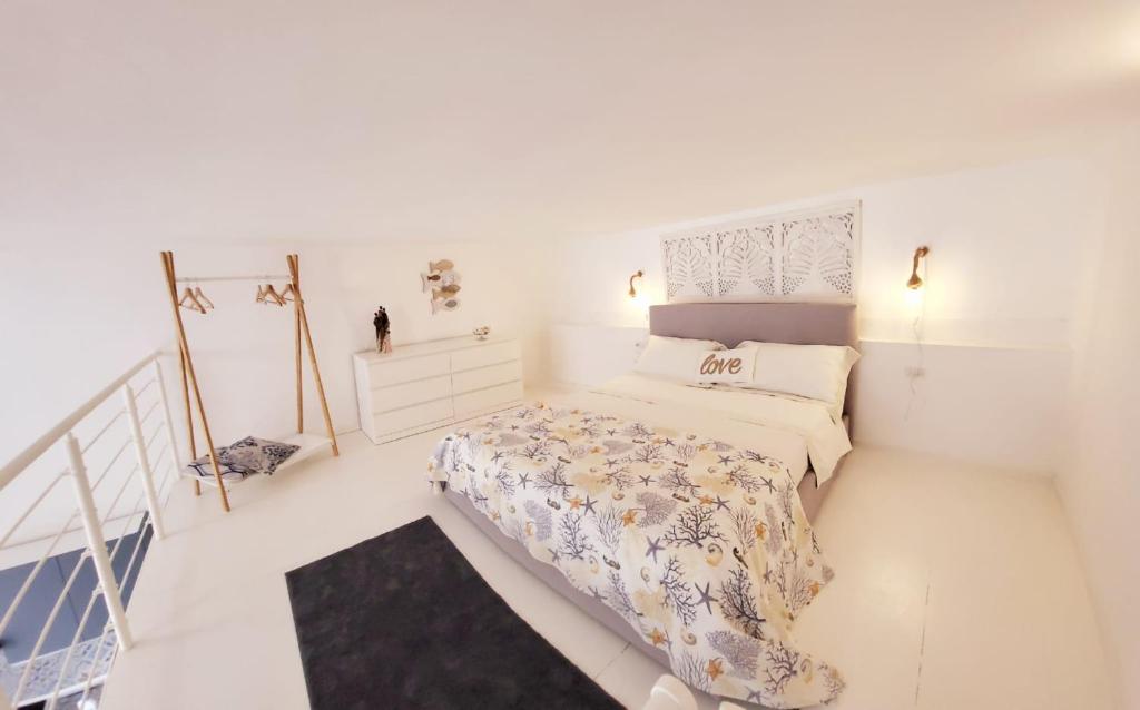 - une chambre blanche avec un lit et un escalier dans l'établissement La Perla Blu, à Calasetta
