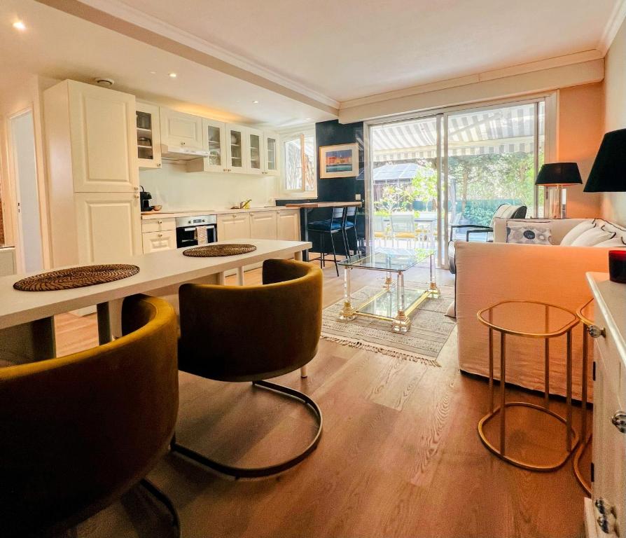 uma cozinha com mesa e cadeiras e uma sala de estar em Superbe appartement avec Terrasse Jardin et Parking privé em Saint-Tropez