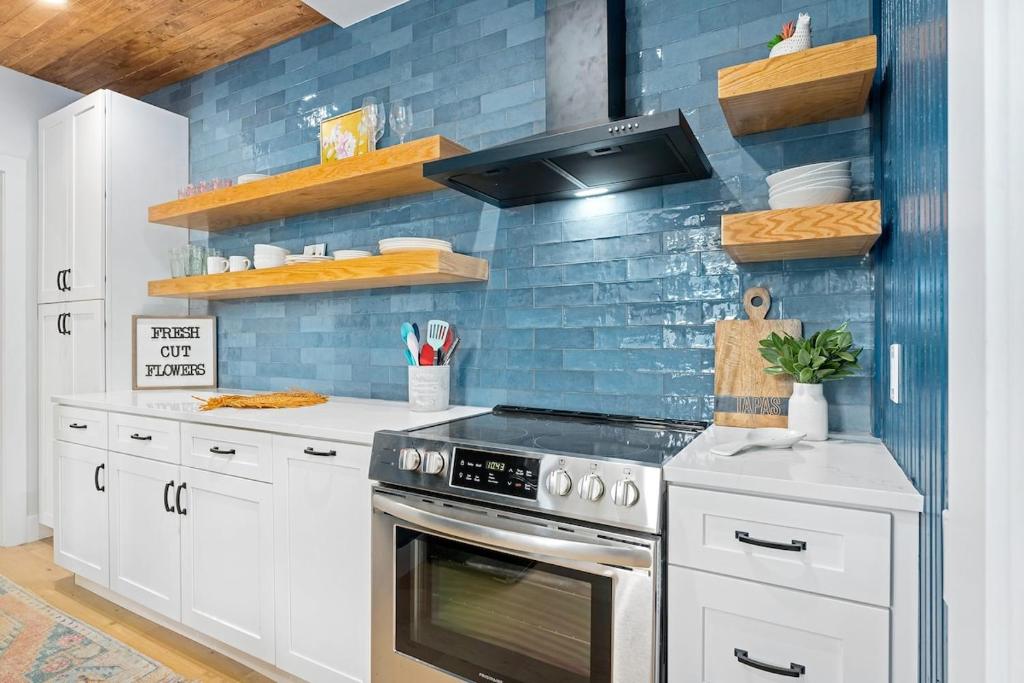 una cocina con armarios blancos y azulejos azules en The Birdhouse - Hot Tub Pool & Fire Pit, en Fredericksburg