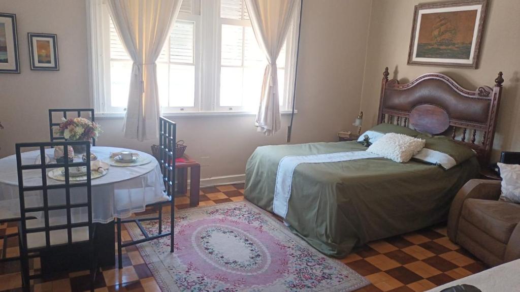 um quarto com uma cama, uma mesa e um sofá em Charmoso Apartamento Retrô no Hotel Quitandinha com vaga de garagem em Petrópolis