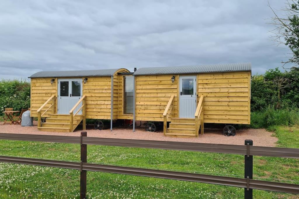 a yellow tiny house sitting next to a fence at Shepherd's View in Ross on Wye