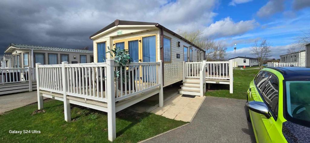 ein kleines Haus mit einem weißen Zaun im Hof in der Unterkunft RJ Luxury caravan hire 2 with Hot Tub in Tattershall