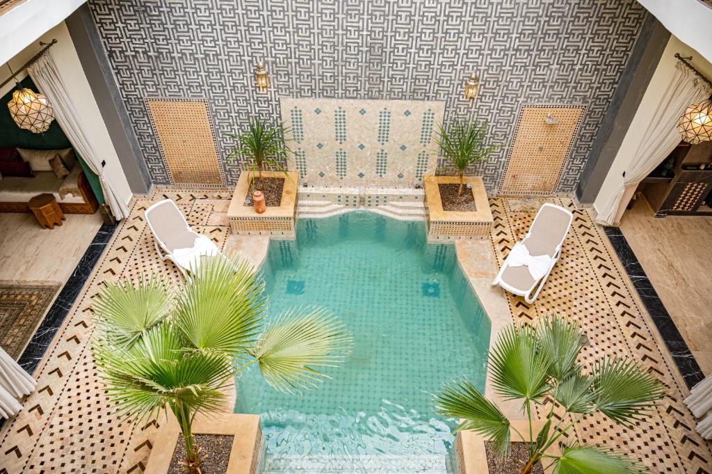 una vista sul tetto di una piscina con sedie e palme di Riad Tonaroz a Marrakech
