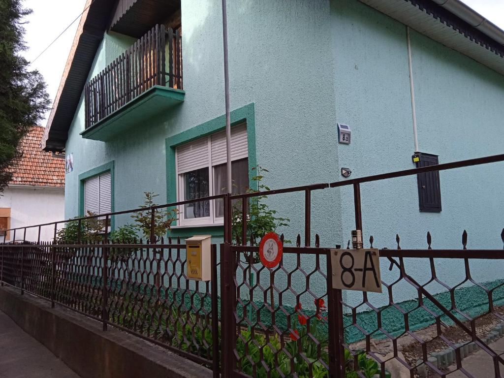 ein blaues Gebäude mit einem Zaun davor in der Unterkunft Julija Pansion in Senta