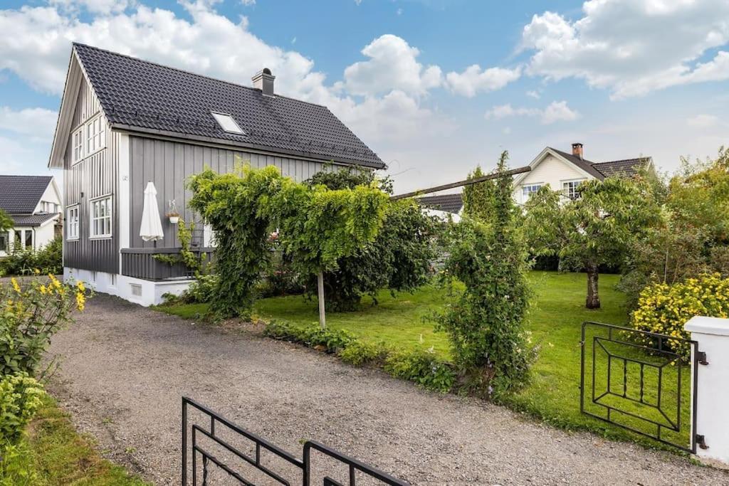 a house with a black roof and a driveway at Sentrumsnær enebolig med 4 soverom in Skien