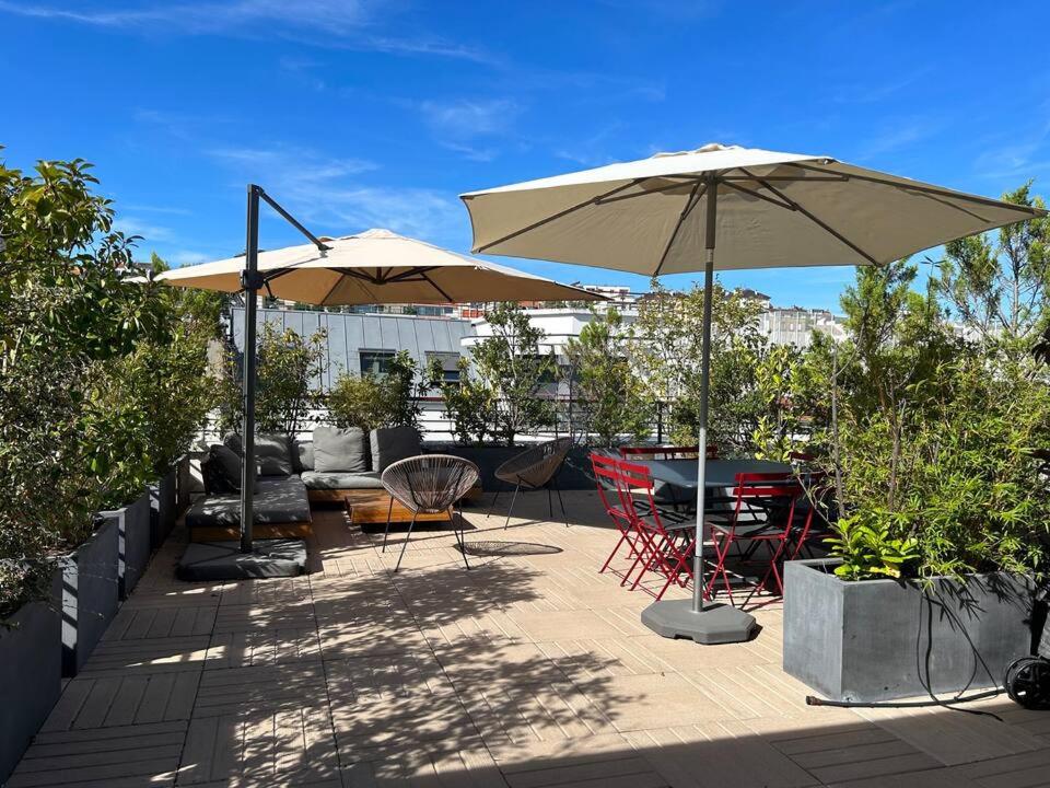 a patio with tables and chairs and an umbrella at Rooftop Suresnes in Suresnes