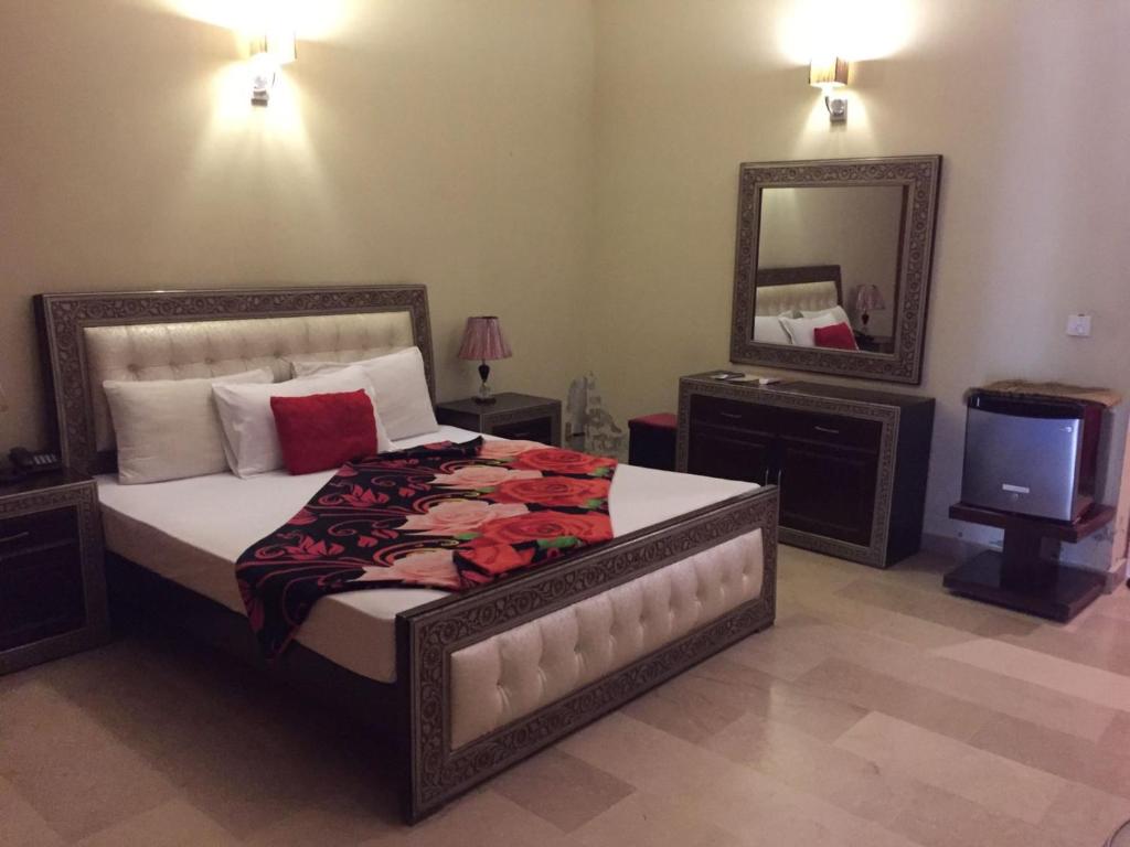 a bedroom with a bed and a mirror and a tv at Royal Galaxy Bed & Breakfast E-11 Islamabad - For Families Only in Islamabad