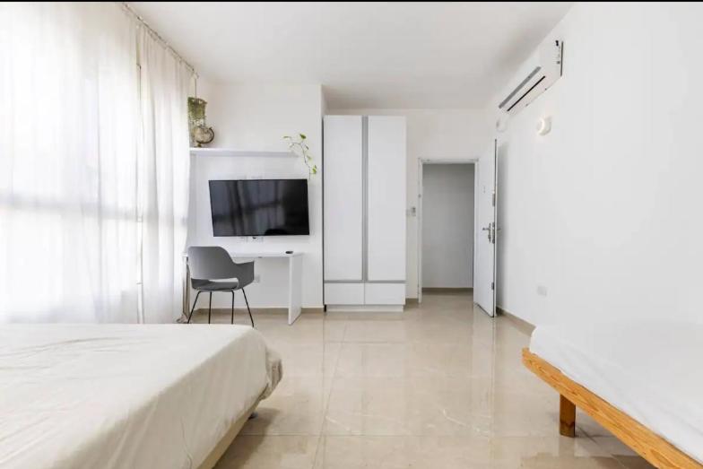 a bedroom with a bed and a desk and a television at Sababa Host-Boutique Rooms in Central Tel Aviv in Tel Aviv