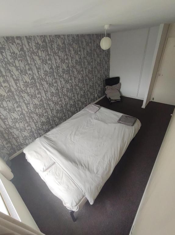 um pequeno quarto com uma cama e uma cadeira em Homestay near a station and park em Longbridge