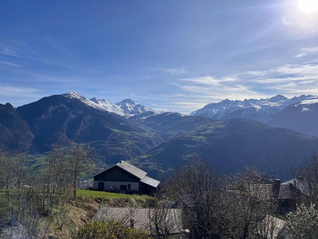 a house on a hill with mountains in the background at LE MOULIN DE NAVETTE -La Roue in Aigueblanche