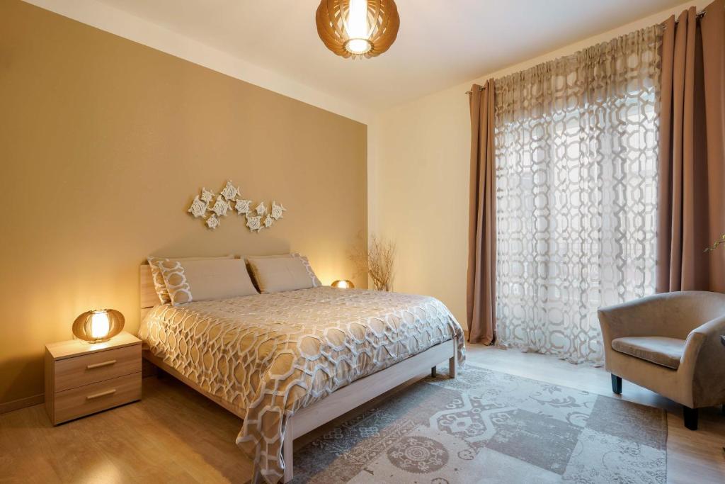 a bedroom with a bed and a chair and a window at Montellinos Suite Tortora in SantʼAntìoco