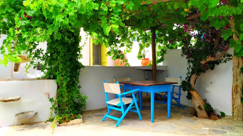 a blue table and a chair under a tree at Grandpa's Traditional Guesthouse in Amorgos