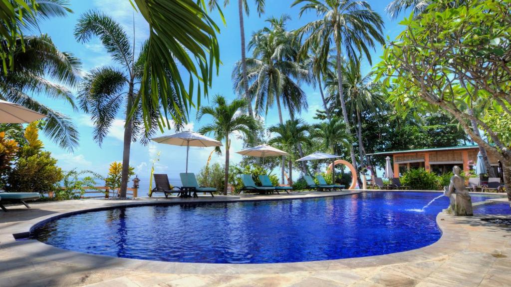 a pool at a resort with palm trees at Holiway Garden Resort & SPA - Bali - CHSE Certified Hotel in Tejakula