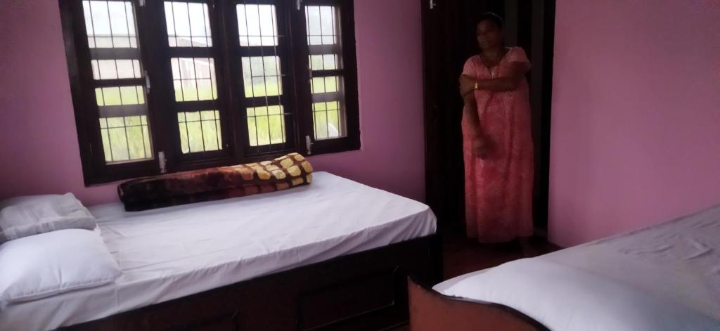 Eine Frau steht in einem Zimmer mit 2 Betten in der Unterkunft Kantipur community homestay in Chitwan