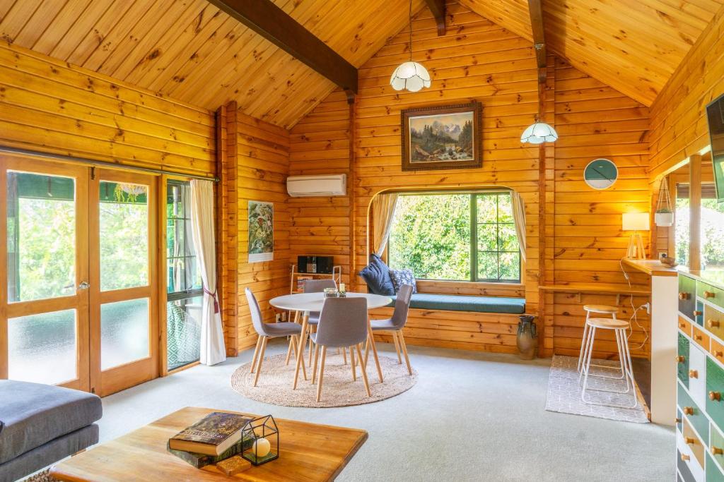 a log cabin living room with a table and chairs at The Birds Nest - Nestled Hideaway in Takaka