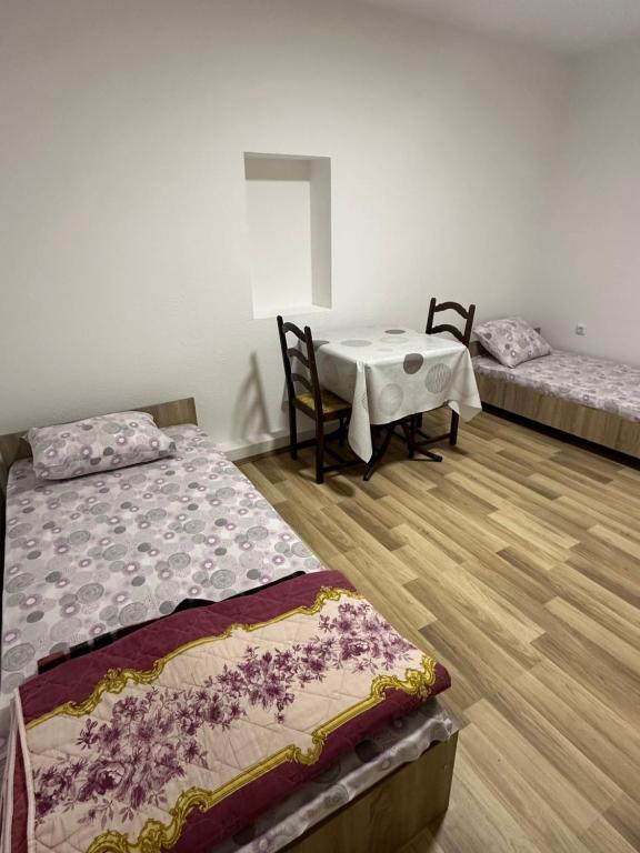 a room with two beds and a table and chairs at gvero apartment’s in Prilep