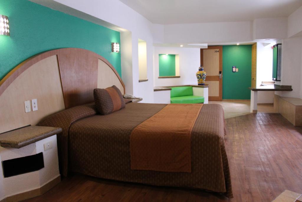 Cette chambre comprend un lit et un mur vert. dans l'établissement Hotel Villa de Madrid, à Mexico