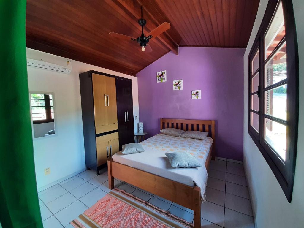 een slaapkamer met paarse muren en een bed in een kamer bij Curral Beach in Ilhabela