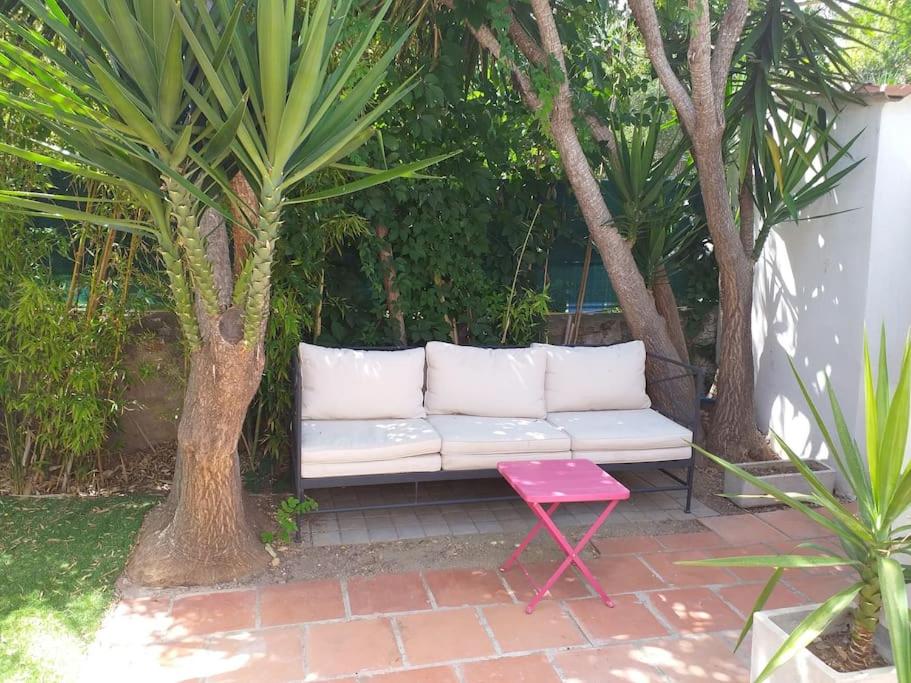 a white couch and a red stool in a garden at Maisonette avec jardinet sur le bas du Faron in Toulon
