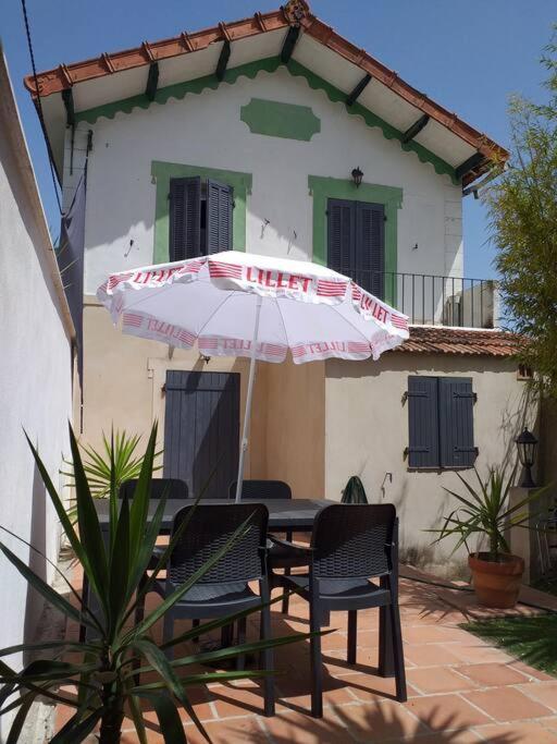 a table and chairs with an umbrella in front of a building at Maisonette avec jardinet sur le bas du Faron in Toulon