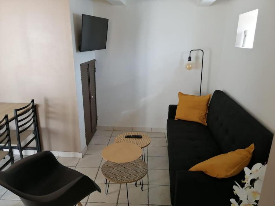 a living room with a black couch and a table at Maisonette avec jardinet sur le bas du Faron in Toulon