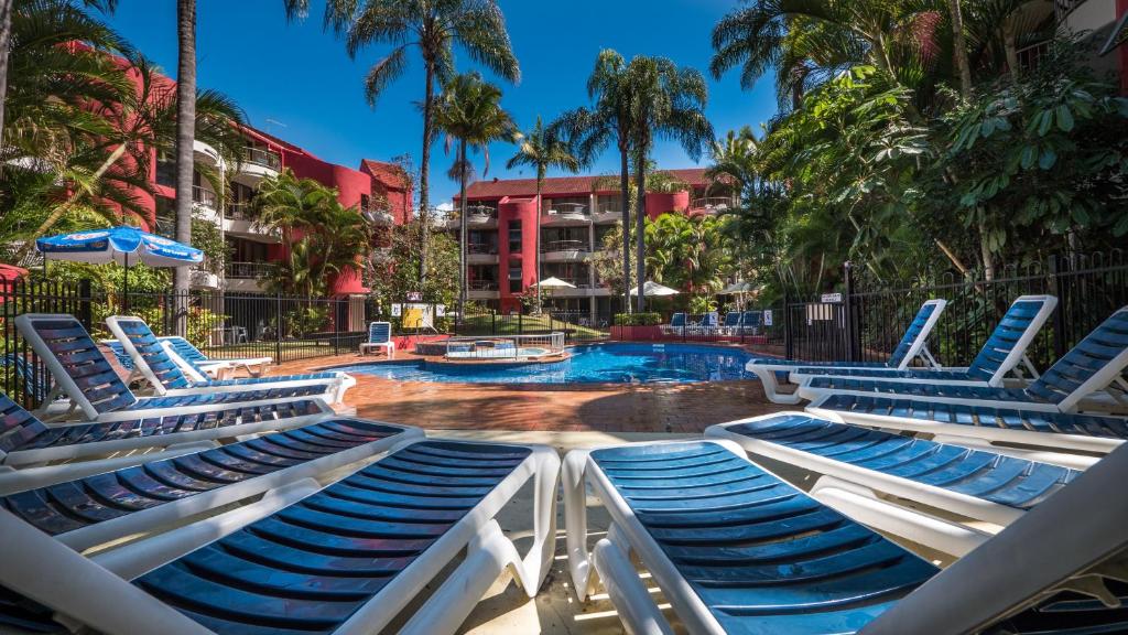 a swimming pool with lounge chairs and a resort at Enderley Gardens Resort in Gold Coast