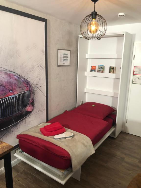 a bedroom with a red bed in a room at Stylisches Maybach Appartement mit Terrasse für 5-7 Personen, 5 Betten, große Kochinsel, Homeoffice mit 250Mbit WLAN in Aidlingen