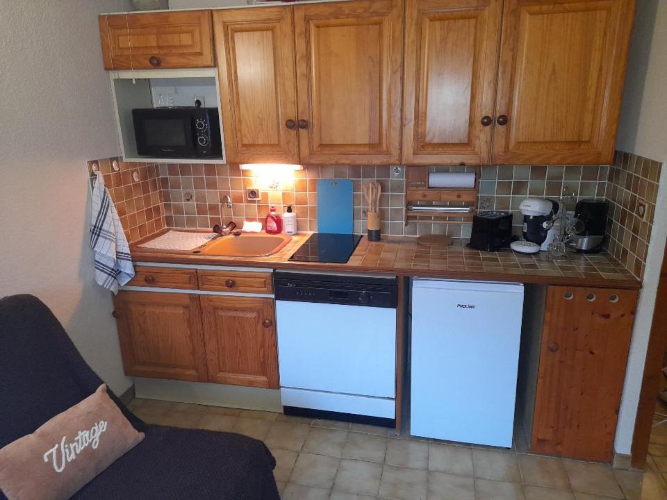 eine Küche mit weißen Geräten und Holzschränken in der Unterkunft Le chalet des neiges 2 in Les Carroz d'Araches