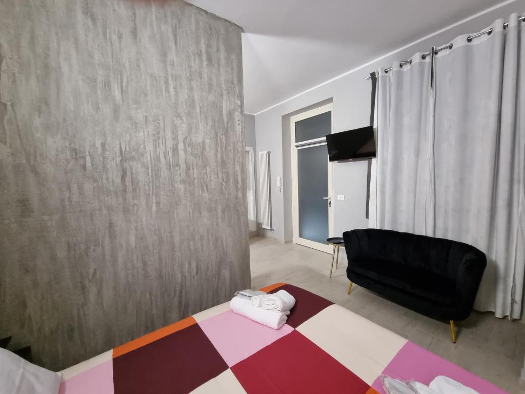 a bedroom with a bed and a black chair at Cà Fiamma 2 in Casale Monferrato