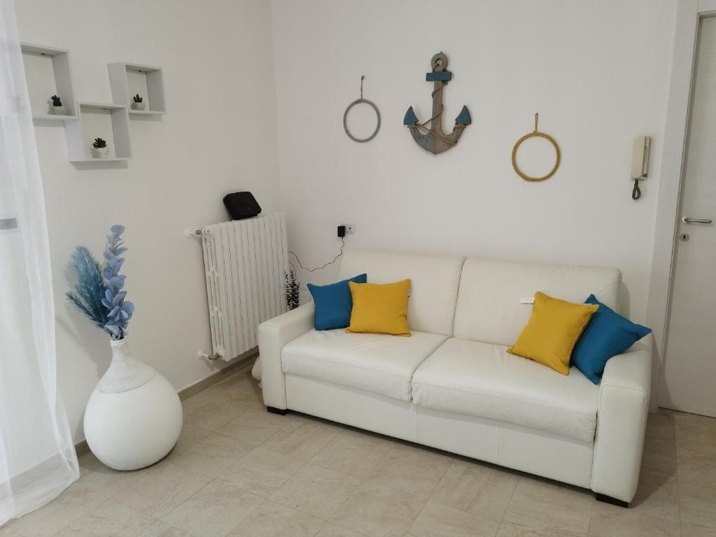 una sala de estar con un sofá blanco con almohadas amarillas y azules en IL BORGO ANTICO - TORRE A MARE, en Torre a Mare