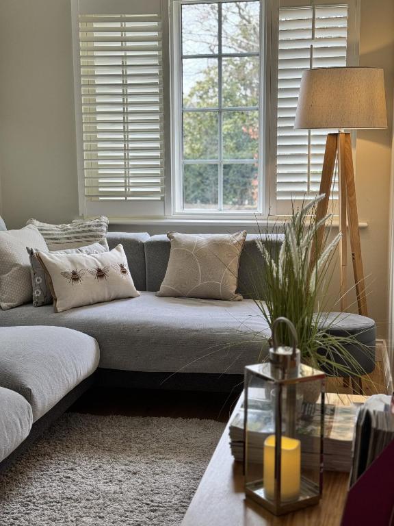 a living room with a couch and two windows at Situated in Stunning Highleigh Village,'BRAMLEY FALL COTTAGE'-Attached Cottage,3 Bedrooms-1 on ground level, SLEEPS 6-2 Bathrooms, 9 mins to Sandy Wittering Beach, 5 mins from Southend Barns, Child friendly,Small Breed Dog Friendly 2 max, Parking-EV Point in Chichester